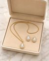 Gold necklace and earrings set in an open jewelry box on a marble surface