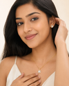 Woman wearing gold necklace and earrings on a beige background