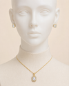 Mannequin wearing gold necklace and earrings on a beige background
