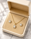 Gold necklace and earrings set in a jewelry box on a marble surface