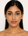 Woman wearing diamond earrings against a white background