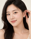 Woman wearing a diamond earring with a plain background