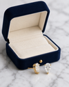 Gold teardrop earrings on a marble surface with a blue jewelry box.
