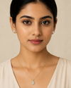 Woman wearing gold necklace and earrings against a beige background