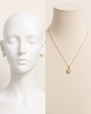 Gold necklace and earrings on a mannequin with a neutral background