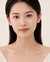 Woman wearing a gold necklace with a small pendant on a plain background
