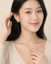 Woman wearing gold earrings and necklace against a neutral background