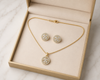 Gold jewelry set with necklace and earrings in a box on a light background