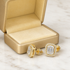 Swarneva Aurelia Emerald-Cut Earring spilling from champagne gold box with pale yellow velvet on white marble