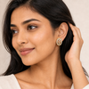 Woman wearing gold earrings with a neutral background