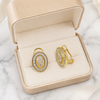 Gold earrings with diamond accents in a beige jewelry box on a marble surface