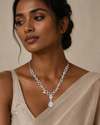 Swarneva Imperial Cadence Necklace worn by a dark complexion Indian female model, silver-tone necklace with white stones, teardrop pendant, dimensions 220 x 15 mm