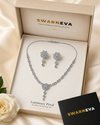 Swarneva Luminary Petal Necklace & Earrings Set arranged inside premium branded jewelry box, silver-tone floral set with clear stones, necklace 220 x 30 mm and earrings 35 x 18 mm.