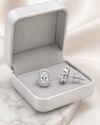 Swarneva Micro-Pave Oval Solitaire Earring spilling from silver-white box with pale grey velvet interior on white marble