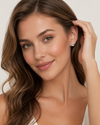Woman with long brown hair wearing a silver earring against a plain background