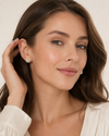 Woman wearing diamond earrings with a neutral background