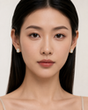 Woman wearing diamond earrings against a neutral background