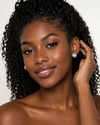 African model tucking hair, Swarneva Round Brilliant Halo Stud, blue icy shimmer visible