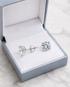Swarneva Round Brilliant Diamond Halo Studs spilling from silver-blue box with white velvet interior on light grey marble