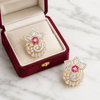 Gold and diamond ring with a pink gemstone in a red velvet box on a marble surface