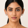 Close-up of a woman wearing diamond earrings against a beige background