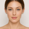 Close-up of a woman wearing diamond earrings against a plain background