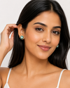 South Asian model tucking hair, Swarneva Valencia Emerald Earring, green halo sparkle visible