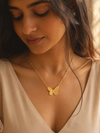 Swarneva Dainty Butterfly Necklace worn by Indian model looking down collarbone, gold 3D butterfly pendant editorial