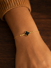 Swarneva Gold Clover Bracelet Black variant worn by Indian model wrist, gold chain black milgrain clover editorial