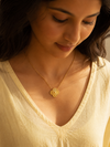 Swarneva Golden Core Bloom Necklace worn by Indian model collarbone looking down, gold bloom pendant editorial
